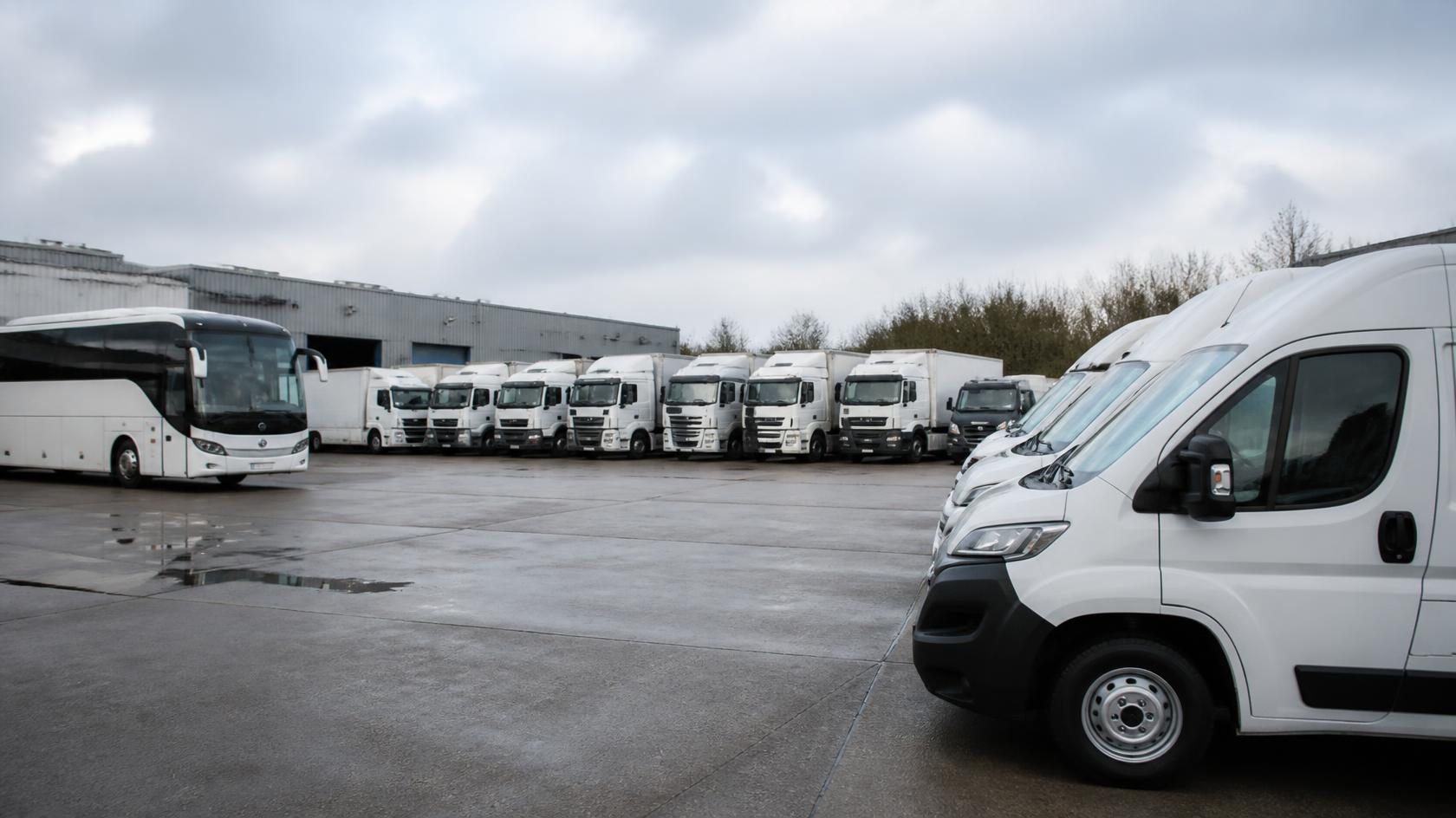 Home 7 UK fleet depot with vans, a curtain-sided lorry and a coach