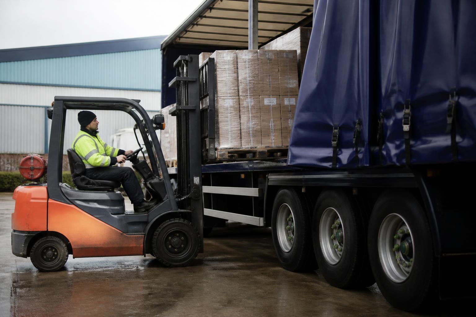 Hire and Reward Insurance 2 Forklift loading a customer's pallets onto a curtain-sided truck at a UK distribution centre